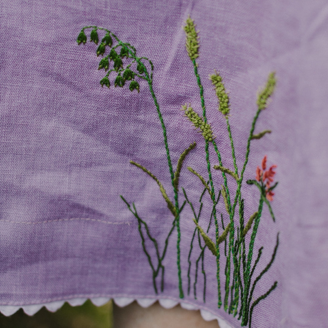 Embroidered plants on purple fabric