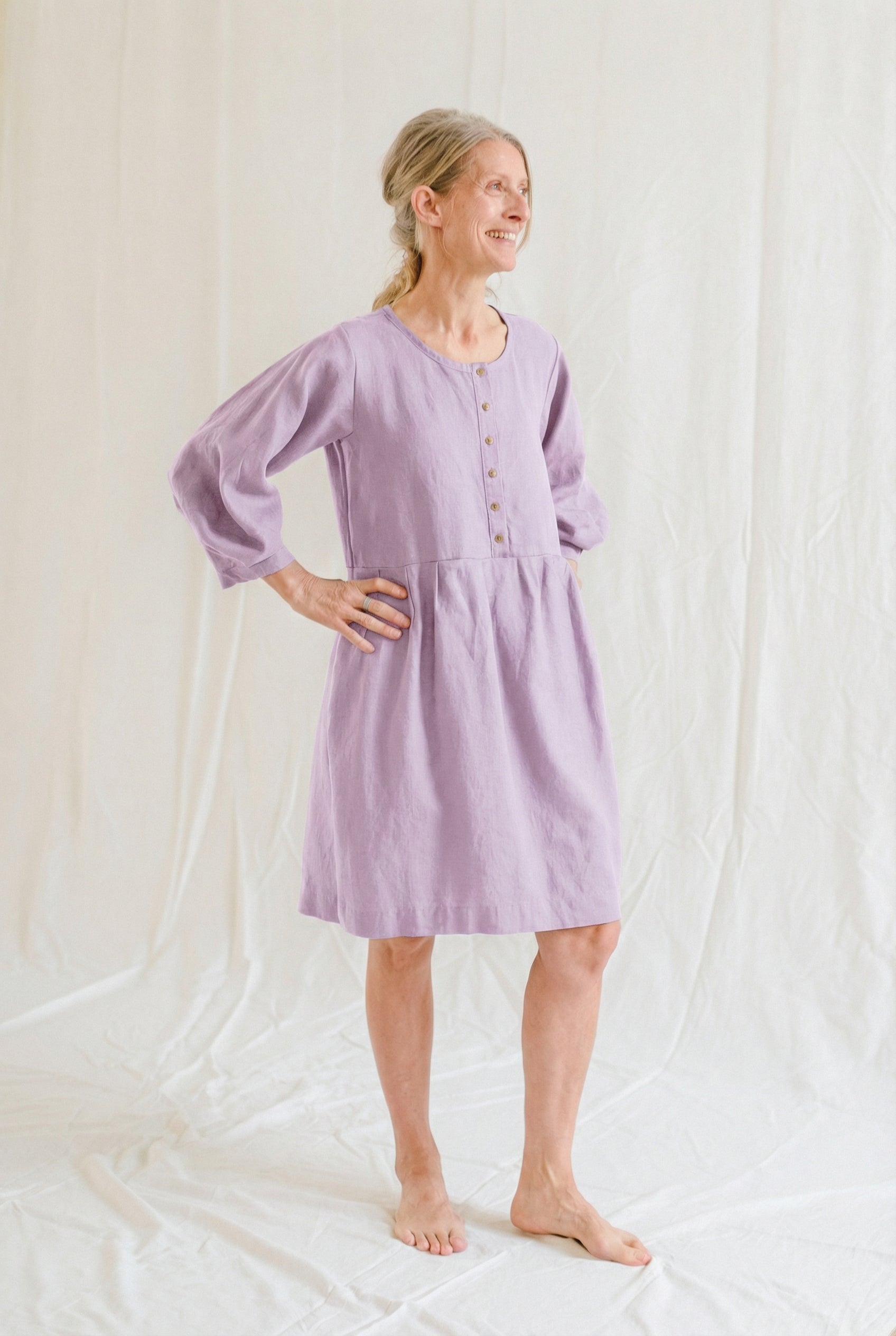 Woman wearing a light purple dress standing against a white background